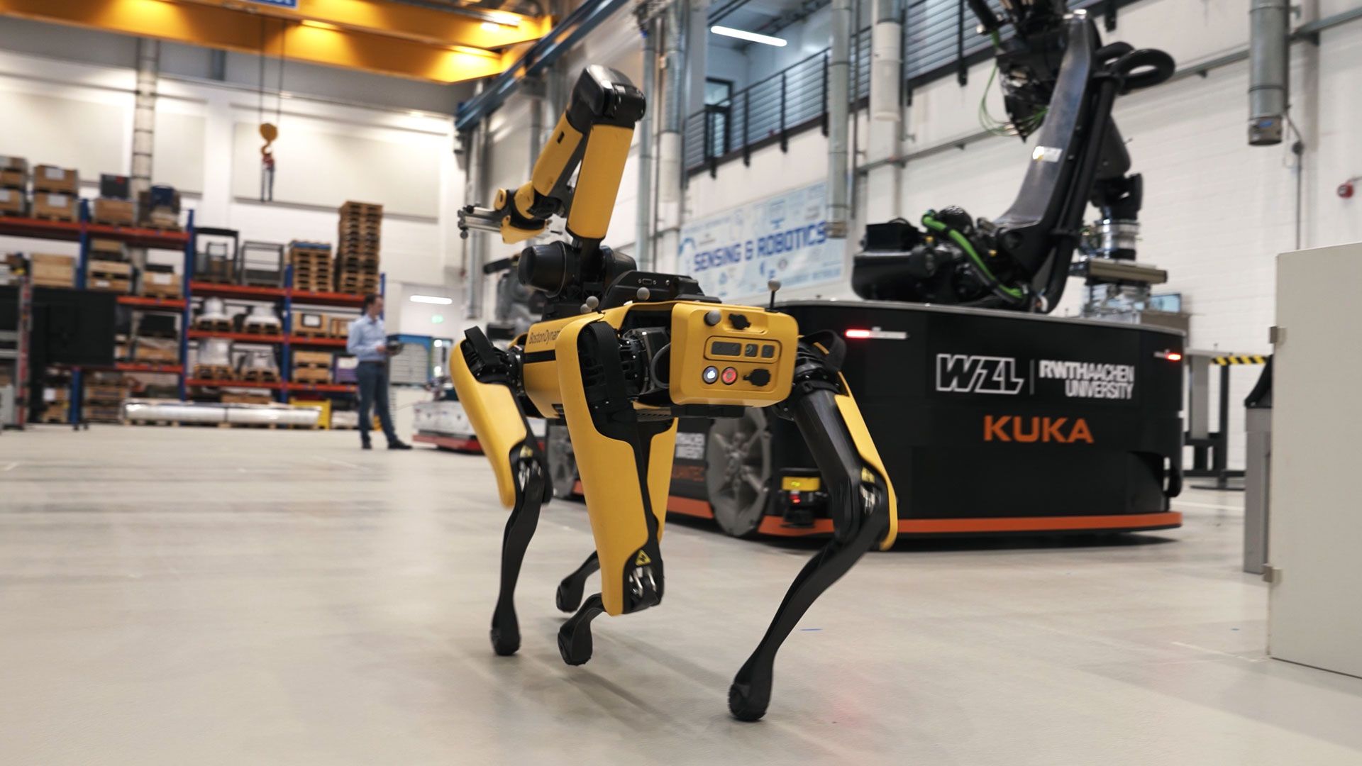Robotic drone dog walking through a warehouse.